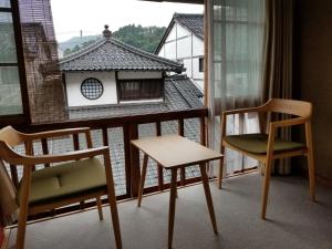 um quarto com duas cadeiras e uma janela em Tsukimotoya Ryokan em Toyooka