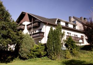 ein großes weißes Gebäude mit Balkonen und Bäumen in der Unterkunft Gästehaus Cordula in Nistertal