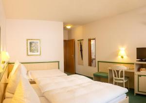 um quarto de hotel com duas camas e uma secretária em Gästehaus Cordula em Nistertal