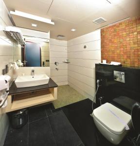 a bathroom with a sink and a toilet and a mirror at Dimora Hotels And Resorts in Trivandrum