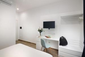 Dieses weiße Zimmer verfügt über einen Schreibtisch und einen TV an der Wand. in der Unterkunft Napoliseason Rooms and Breakfast in Neapel