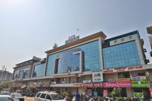 a large glass building with cars parked in front of it at HOTEL HARMONY in Vadodara
