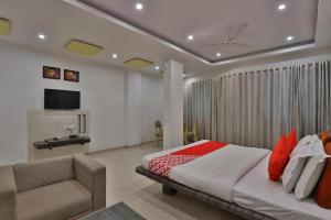 a bedroom with a bed and a couch and a television at HOTEL HARMONY in Vadodara