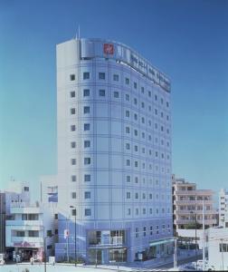 un edificio blanco alto con un letrero. en DAI-ICHI INN SHONAN, en Fujisawa