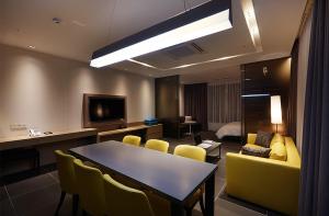 a room with a table and chairs and a television at Osong H Hotel Sejong City in Cheongju