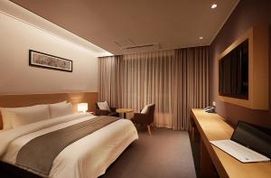 a hotel room with a bed and a desk with a computer at Osong H Hotel Sejong City in Cheongju +19 photos