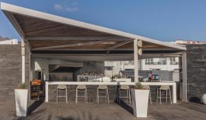 a patio with a bar with stools under a roof at Flamingo Beach Mate in Adeje