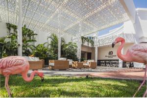 two pink flamingos standing in the grass in front of a building at Flamingo Beach Mate in Adeje