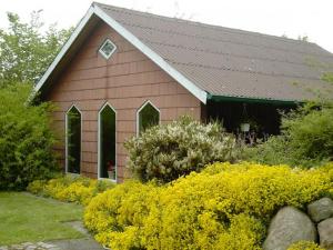 a brown barn with windows and some yellow flowers at Blutbuchenhof in Erfde
