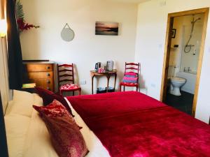 a bedroom with a large red bed with two chairs at Burnside Lodge in Portnahaven