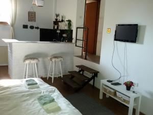 a room with a bed and two stools and a tv at Apartman Sissi in Pančevo