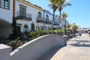 a white building with palm trees and a sidewalk at Charming Oceanfront House in Puerto de Mogn, Gran Canaria in Puerto de Mogán +33 photos