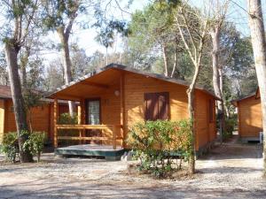 een houten hut met een veranda in het bos bij Campeggio Boscoverde in Torre del Lago Puccini