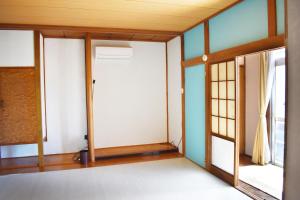 ein leeres Zimmer mit einer Tür und einem Fenster in der Unterkunft Volcanic Island in Oshima