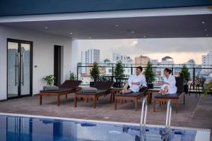 two men sitting on chairs next to a swimming pool at Residence 105 Hotel and Apartment in Phnom Penh
