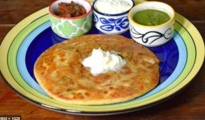 a plate of food with a pancake on a table at HOTEL HARMONY in Vadodara