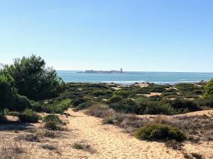 a dirt road leading to the ocean with a lighthouse in the distance at Apartamento Zinna in Chiclana de la Frontera