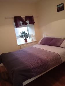 a bedroom with a bed with purple sheets and a window at 11 Malin Street, Noreens place in Carndonagh