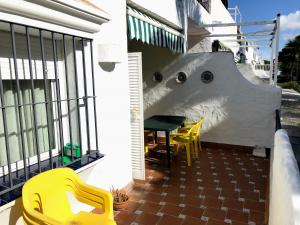 a balcony with yellow chairs and a table on a house at Apartamento Zinna in Chiclana de la Frontera