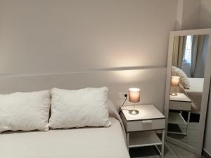 sypialnia z białym łóżkiem i lustrem w obiekcie Chimihome w Kordobie