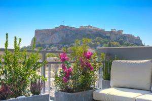 eine Couch auf dem Balkon mit Blumen in der Unterkunft Hidesign Athens Acropolis Panorama Suite in Athen