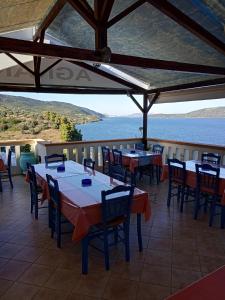 um restaurante com mesas e cadeiras e vista para a água em Agnanti Hotel em Kalamakia