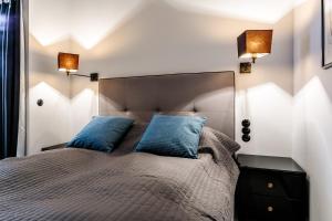 um quarto com uma cama grande e 2 almofadas azuis em 3D WYGODA Apartamenty em Cracóvia