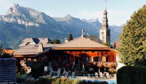 a building with a clock tower with mountains in the background at Le Coin Savoyard in Combloux