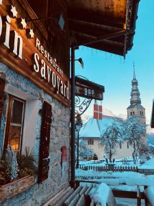 un bâtiment avec un panneau indiquant un restaurant et une église dans l'établissement Le Coin Savoyard, à Combloux