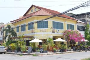 a yellow building with umbrellas in front of it at Hotel La Java Bleue in Kampot