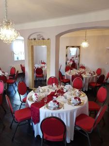 a dining room with tables and red chairs at HERRENHAUS KUNZWERDA bei TORGAU - ApartHotel, BoardingHouse, WOHNEN auf ZEIT in Torgau