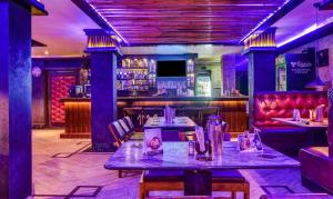 um restaurante com mesas e um bar com iluminação roxa em Itsy By Treebo - The Villa Retreat em Siliguri