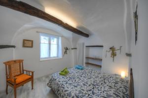 a bedroom with a bed and a chair and a window at ANTICA CASA DEL CANTO Iara in Calice Ligure