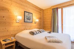 Schlafzimmer mit einem Bett mit Holzwänden und einem Fenster in der Unterkunft Résidence Les Chalets du Forum - Courchevel 1850 in Courchevel