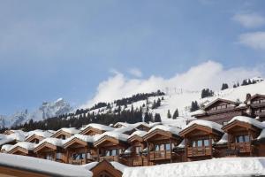 a snow covered lodge with a mountain in the background at Résidence Les Chalets du Forum - Courchevel 1850 in Courchevel