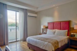 a bedroom with a large bed and a large window at Mansion Garden Hotel in Olongapo