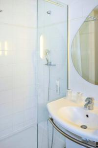 La salle de bains blanche est pourvue d'un lavabo et d'une douche. dans l'établissement ibis budget Bordeaux Lac, à Bordeaux