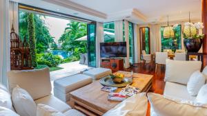 a living room with white furniture and a large window at Villa in the Garden, Surin Beach with private spa. in Surin Beach
