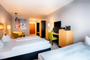 a hotel room with two beds and a desk at ACHAT Hotel Egelsbach Frankfurt in Egelsbach