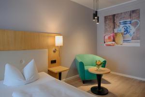 a bedroom with a bed and a chair and a table at ACHAT Hotel Egelsbach Frankfurt in Egelsbach