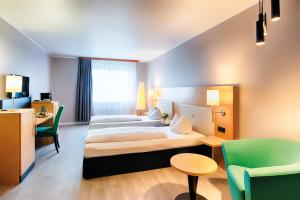ein Hotelzimmer mit 2 Betten, einem Tisch und Stühlen in der Unterkunft ACHAT Hotel Egelsbach Frankfurt in Egelsbach