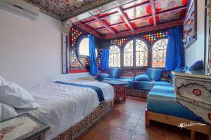 Hotel Madrid في شفشاون: غرفة نوم بسرير واريكة ونافذة