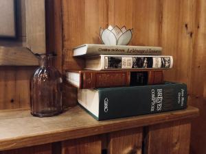 a stack of books sitting on a shelf with a glass bottle at Le Coin Savoyard in Combloux