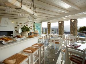a restaurant with a breakfast bar with white stools at Leonis Summer Houses in Ornos
