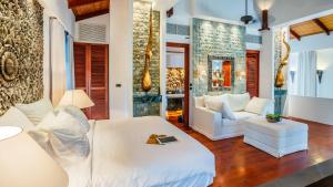 a bedroom with a white bed and a couch at Villa in the Garden, Surin Beach with private spa. in Surin Beach +21 photos