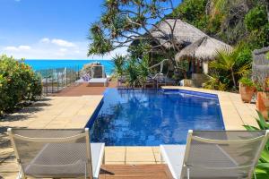 a pool with chairs and the ocean in the background at Liapari Beach House in Sapphire Beach