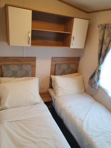 two beds in a small room with white sheets at Shorefield country Park, in Milford on Sea