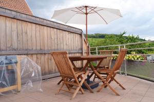 een houten tafel met 2 stoelen en een parasol bij Gîte Binnert Bader in Nothalten