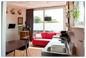 een woonkamer met een rode bank en een tafel bij Private guesthouse BnB The Waterhouse houseboat in Amsterdam