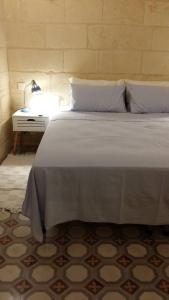 1 dormitorio con 1 cama y mesita de noche con lámpara en Magic in the Heart of Old Gozo (Penthouse), en Victoria